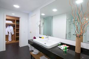 Badezimmer im Fuerteventura Princess Hotel mit weißem Waschbecken, Spiegel und blauen Dekorationselementen.