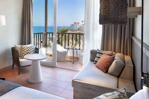 Innenansicht einer Suite im Fuerteventura Princess Hotel mit Blick auf den Ozean und einem möblierten Balkon.