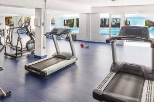 Fitnessstudio im Fuerteventura Princess Hotel mit verschiedenen Geräten und Blick auf den Pool.