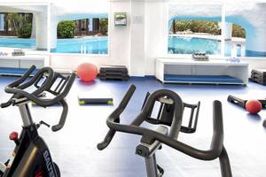Fitnessraum im Fuerteventura Princess Hotel mit Blick auf den Pool und Trainingsgeräten.