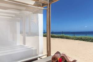 Außenbereich des Fuerteventura Princess Hotels mit einem Strandbett, Strandtüchern und einem kühlen Getränk.
