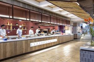 Innenansicht des Restaurants im Fuerteventura Princess Hotel mit Köchen, die an einer langen Theke arbeiten und verschiedene Früchte auf dem Tisch sind.