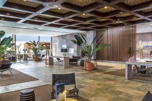 Lobby des Fuerteventura Princess Hotels mit vielen Pflanzen, Möbeln und einer Lampe.