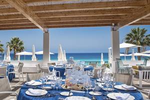 Außenbereich des Fuerteventura Princess Hotels mit blauen Tischen und Stühlen, Blick auf das Meer.