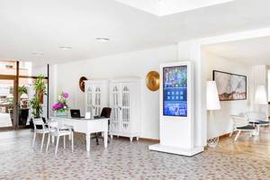 Empfangsbereich des Occidental Jandia Royal Level Hotels mit einem Tisch, Stühlen, Fernseher und Dekor.