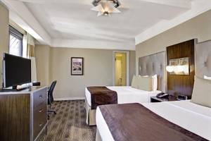 Doppelbett-Zimmer im New Yorker Hotel mit Fernseher, Schreibtisch und Nachttischen.