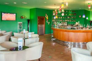 Lobby-Bar des Occidental Jandia Royal Level mit grünen Wänden, Bartheken, Kronleuchtern und Sitzbereichen.