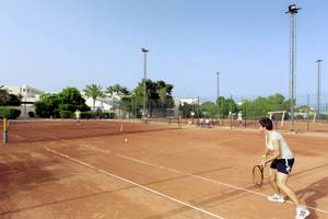 Tennisplatz im Calimera Yati Beach Hotel mit Spielerin, die einen Ball schlägt.
