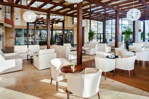 Ein Hotellobby mit weißen Sofas, Holzboden und modernen Kronleuchtern.