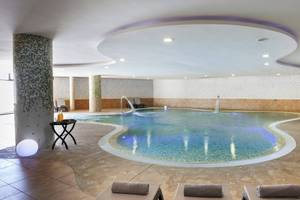 Innenpool des Occidental Jandia Mar Hotels mit Loungeliegen und Wasserfontänen.