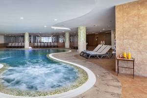 Innenpool im Occidental Jandia Mar Hotel mit Lounge-Liegestühlen und Wasserspender.