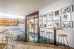 Innenansicht der Bar im Occidental Jandia Mar Hotel mit Tischen, Stühlen und Fotowänden.
