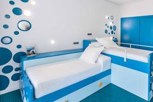 Doppelzimmer im Occidental Jandia Mar Hotel mit blauer und weißer Inneneinrichtung, zwei Betten, weißen Kissen und blauen Schranktüren.