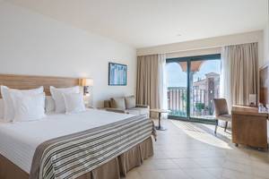 Hotelzimmer im Occidental Jandia Mar mit Balkon, Bett, Couch und Schreibtisch.