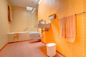 Badezimmer im SBH Monica Beach Resort mit gelben Fliesen, Badewanne und Toilette.