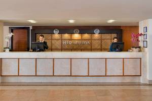 Die Rezeption des H10 Tindaya Hotels mit zwei Angestellten und dekorativen Pflanzen.