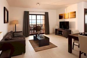 Wohnzimmer des Melia Tortuga Beach Hotels mit Sofa, Tisch, Fernseher und Balkon.