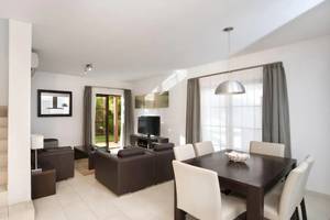 Wohnbereich des Melia Tortuga Beach Hotels mit weißen Wänden, einer Treppe, einem Sofa und einem Fernseher.