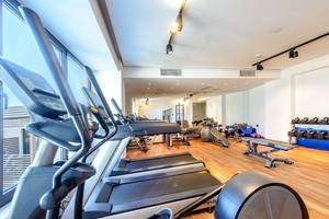 Fitnessraum im Stella Island Luxury Resort & Spa mit mehreren Laufbändern und Hanteln.