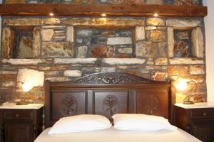 Schlafzimmer in der Villa Romantica mit Steinwand, betten und Nachttischen.