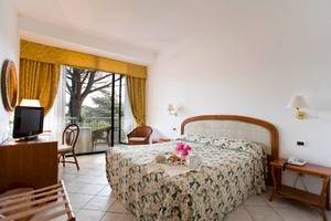 Ein Schlafzimmer im Sierra Silvana Hotel mit Balkon, Fernseher, und Blumenbettwäsche.
