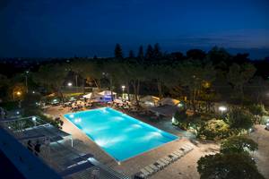 Luftaufnahme des beleuchteten Außenpools und der Terrasse des Hotels Sierra Silvana bei Nacht