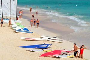 Strandszene im Bahia Principe Grand Bavaro Hotel mit vielen Gästen, Sonnensegeln und Wassersportgeräten