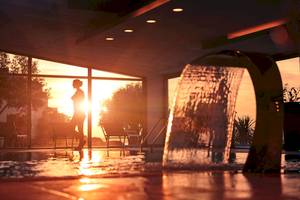 Sonnenuntergang im Poolbereich des Valamar Argosy Hotels mit einer Person und Wasserfall