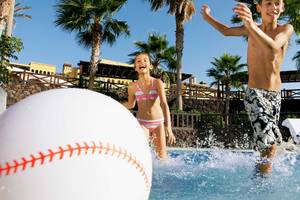Kinder spielen mit einem großen Baseball im Pool im Occidental Jandia Playa Hotel.