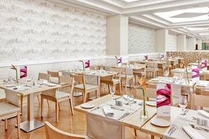 Innenansicht des Restaurants im Occidental Jandia Playa Hotel mit gedeckten Tischen und weißen Wänden.
