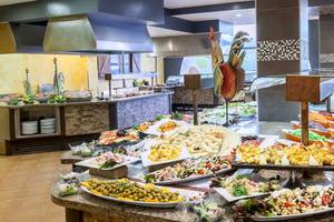 Buffetbereich im Occidental Jandia Playa Hotel mit verschiedenen Speisen und Salaten auf Marmortischen.