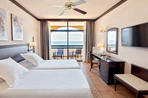 Doppelzimmer im Occidental Jandia Playa Hotel mit Meerblick, zwei Betten, Schreibtisch und Fernseher.