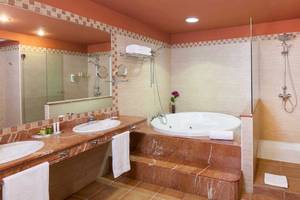 Badezimmer im Occidental Jandia Playa Hotel mit Badewanne, Dusche und Waschbecken.