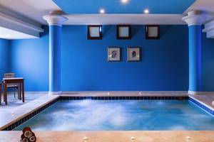 Ein blauer Innenpool des Jaz Lamaya Resorts mit Tisch und Stühlen.