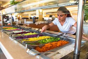 Eine Frau bedient das Buffet im Messonghi Beach Holiday Resort mit verschiedenen Salaten und Beilagen.