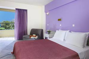 Schlafzimmer im Giannoulis Santa Marina Beach Hotel mit lila Wand, Bett, Kissen, und Balkon.