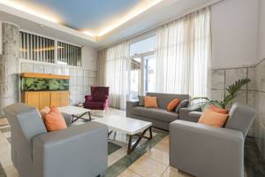 Wohnbereich im Kosta Palace City Hotel mit Sofas, Stühlen und einem Aquarium.