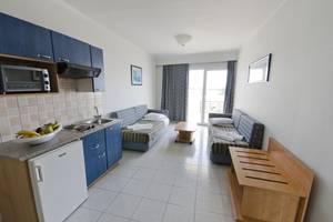Innenansicht eines Zimmers im Kosta Palace City Hotel mit Küchenbereich und Schlafsofas.