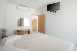 Doppelzimmer im Kosta Palace City Hotel mit zwei Betten, Klimaanlage und Fernseher an der Wand.