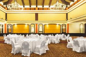 Bankettsaal im Le Meridien Ile Maurice mit weißen Tischen und Stühlen, goldenen Wänden und Kronleuchtern.