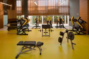 Fitnessstudio im Titanic Deluxe Golf Belek Hotel mit gelbem Boden und Trainingsgeräten