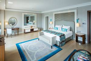 Ein modernes Hotelzimmer im Titanic Deluxe Golf Belek mit einem großen Bett, Schreibtisch und Spiegel.