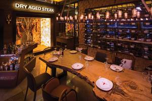 Restauranttisch mit sechs Stühlen, vor dem Schild Dry Aged Steak