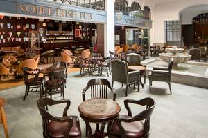Innenansicht des Noble Irish Pub mit Lederstühlen, Tischen und einer Bar.