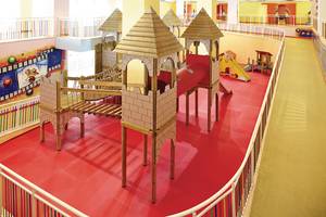 Kinderspielplatz im Titanic Deluxe Golf Belek Hotel mit bunten Holzburgen und roter Spielfläche.