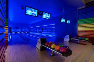 Bowlingbahn im Hotel Titanic Deluxe Golf Belek mit blauer Beleuchtung und bunten Wänden.