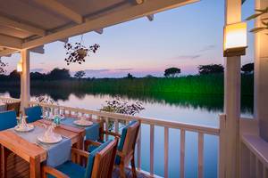 Terrasse des Titanic Deluxe Golf Belek Hotels mit Blick auf einen See bei Sonnenuntergang.