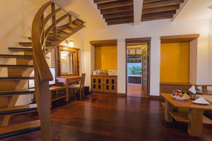 Inneneinrichtung eines Zimmers im Bandos Maldives Hotel mit hölzerner Treppe und Möbeln.