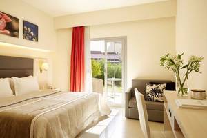 Hotelzimmer im Capo Di Corfu mit Bett, Tisch, Couch und Balkon.