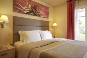 Schlafzimmer im Capo Di Corfu Hotel mit Bett, Kissen, Lampen und Fenster.